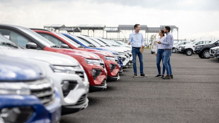 Kunden kaufen beim Autohändler einen Gebrauchtwagen